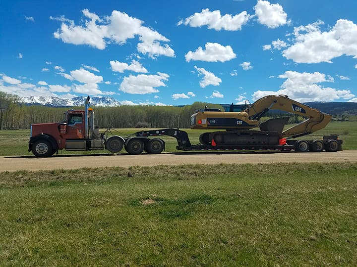 Heavy equipment on a transport trailer with Colorado mountains behind it, from MSI’s project gallery